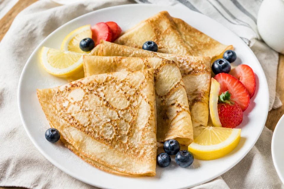 Thin finished French crepes folded into triangles and served with lemon wedges and fresh berries.