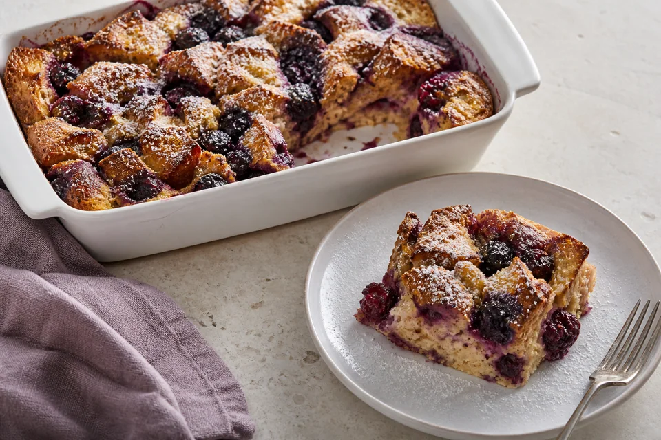 Golden blackberry French toast bake with whole berries and a plated square revealing fruit pockets in the set custard.
