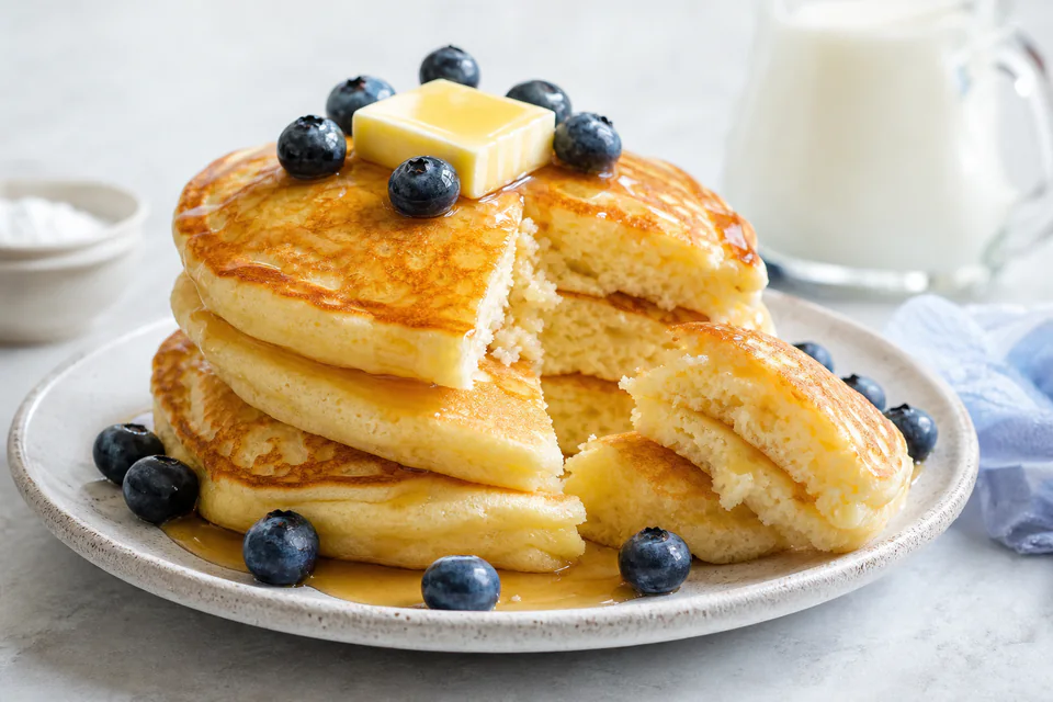 Finished fluffy pancakes torn open to show a light cooked crumb with butter and blueberries
