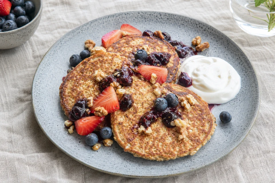 Finished oat and banana pancakes with berries, walnuts, fruit compote, and plain yogurt.