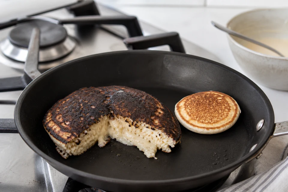 A very dark thick pancake cut open to reveal a wet centre beside a smaller cooked control pancake.
