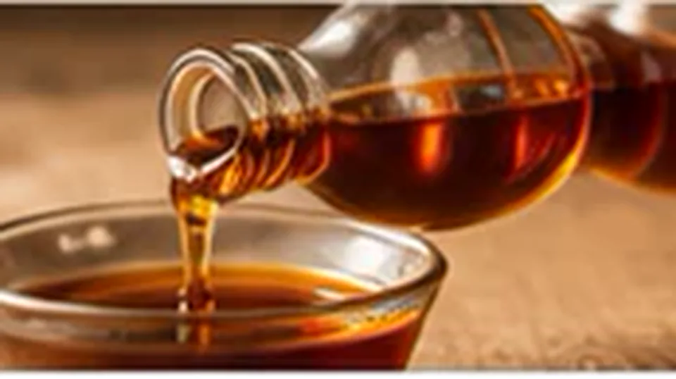 Maple syrup served beside a warm pancake breakfast.
